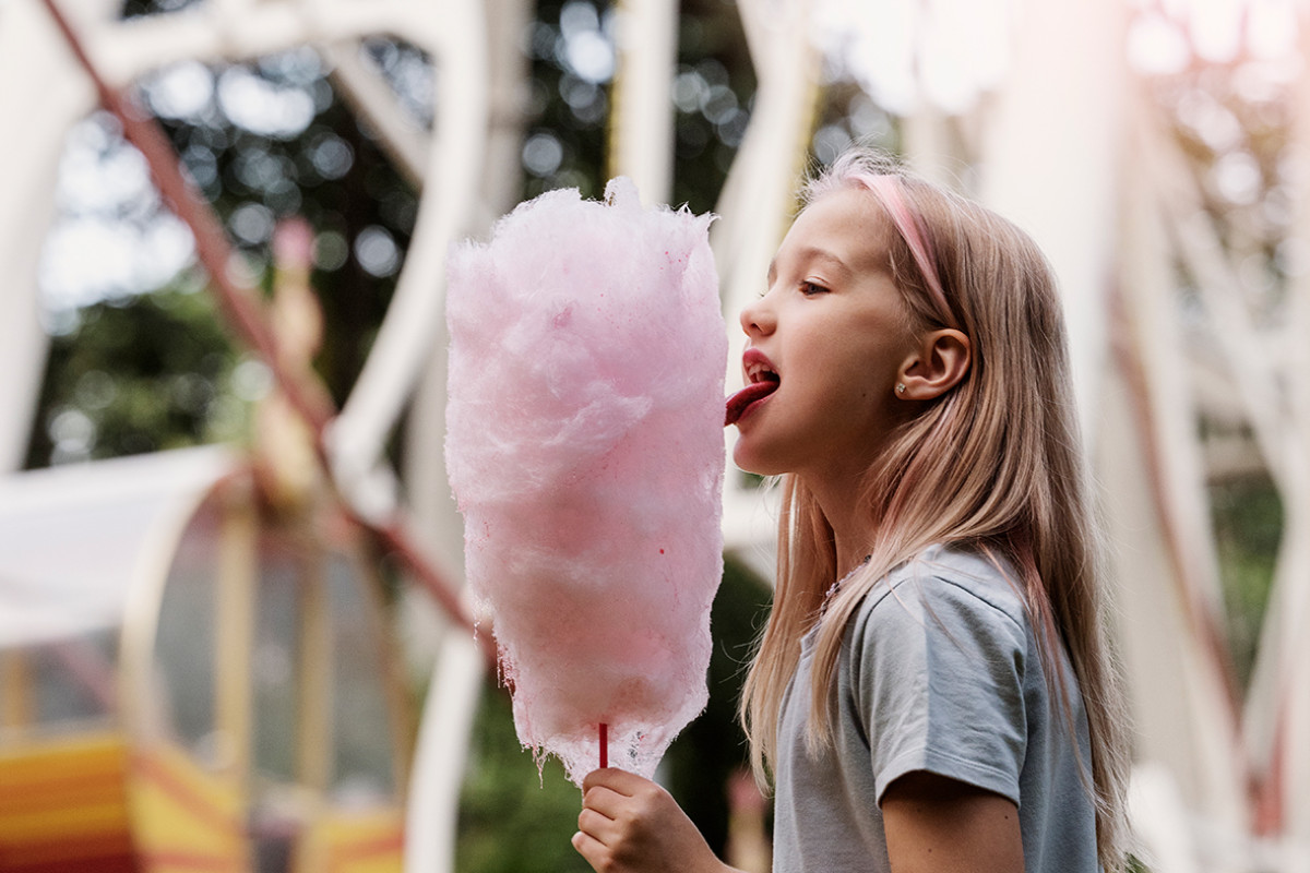 Meisje eet een grote roze suikerspin