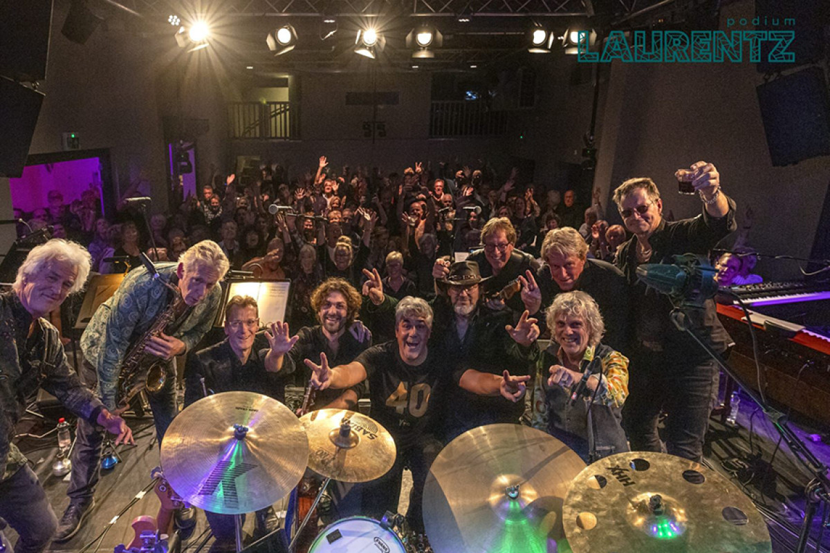 Grote band staat op het podium, op de achtergrond is het publiek te zien