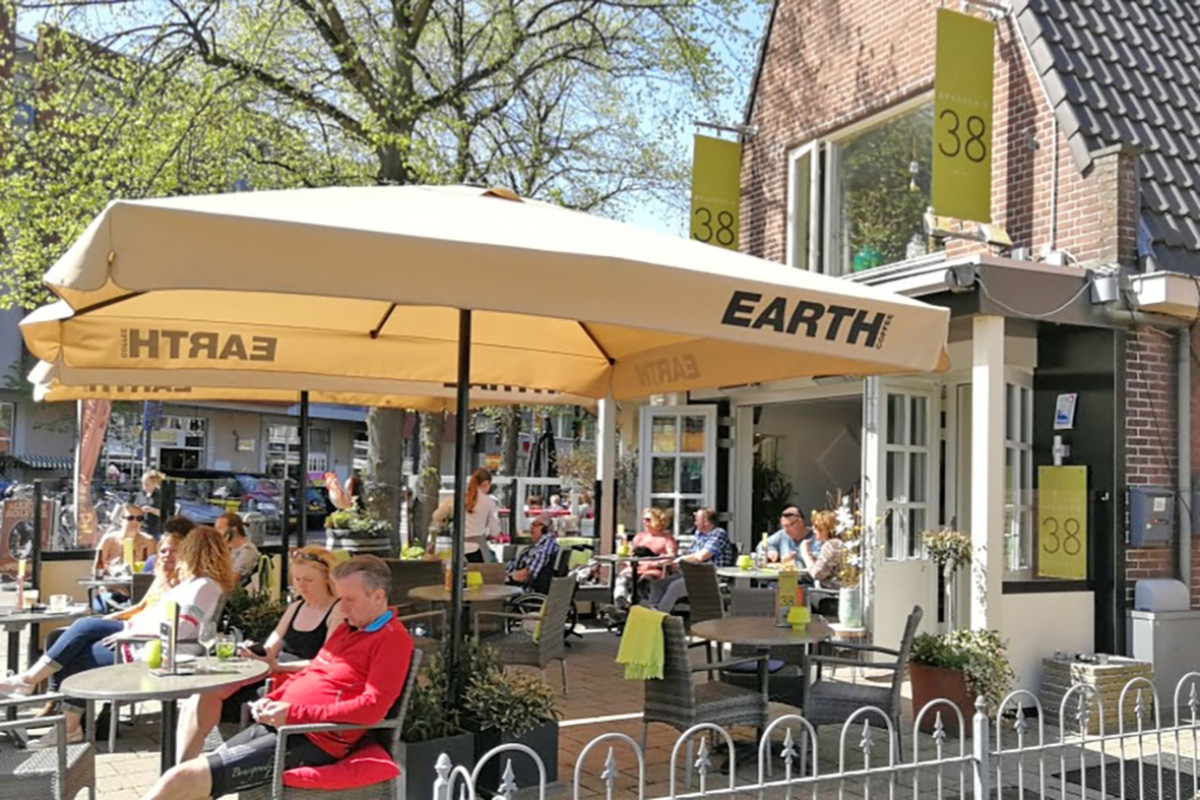 Zonnig terras van Restaurant Brasserie 38 waar mensen onder de parasol zitten.