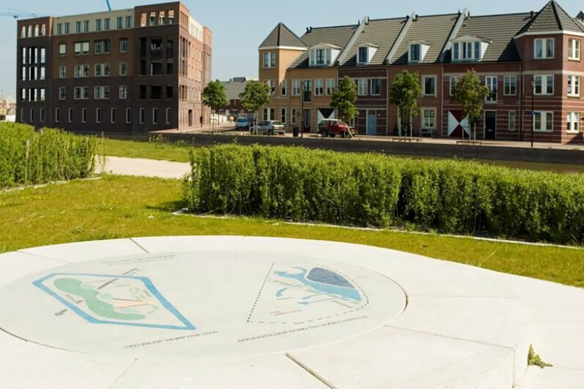 Een kaart van de stad wordt weergegeven op een stenen bank met in de achtergrond wijk Broekpolder.