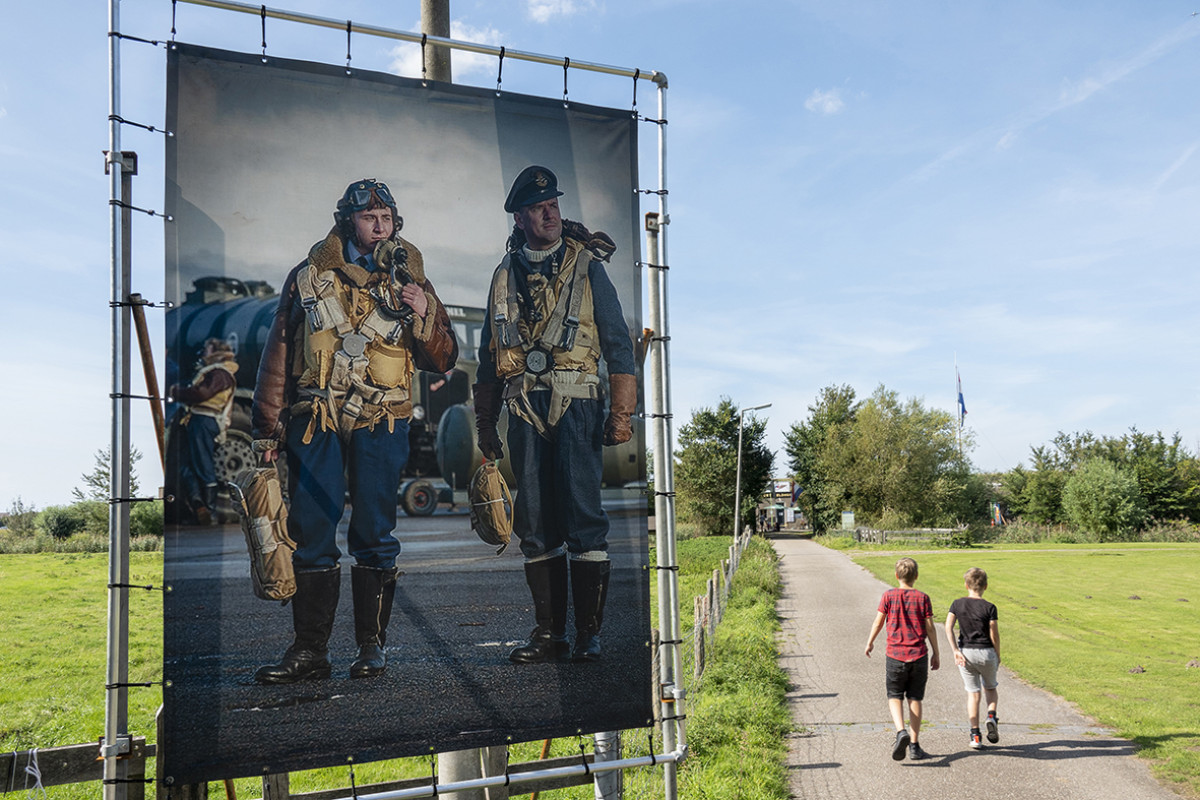 Afbeelding van vliegeniers buiten in landelijk landschap, twee jongens lopen op pad.