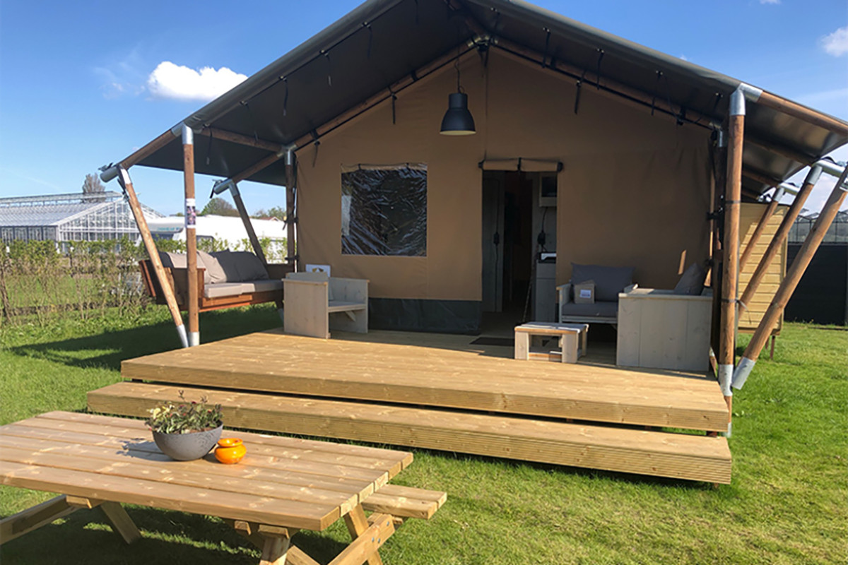 Een safaritent met een tafel en stoelen op het gras.