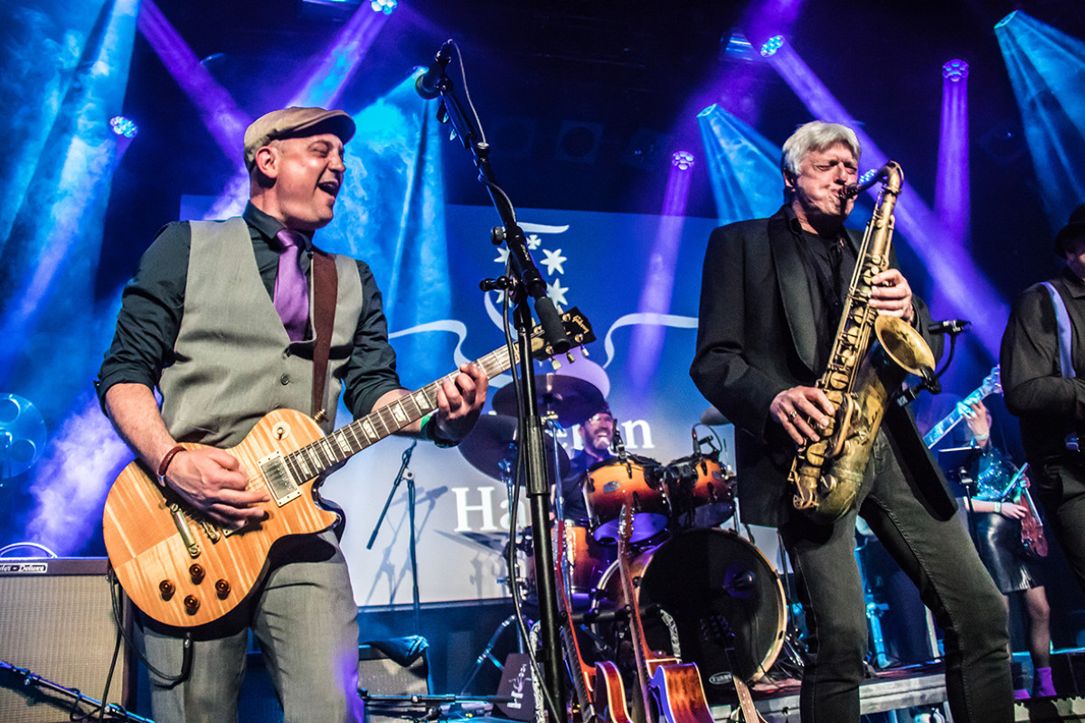 Twee mannen op een podium met een gitaar en saxofoon