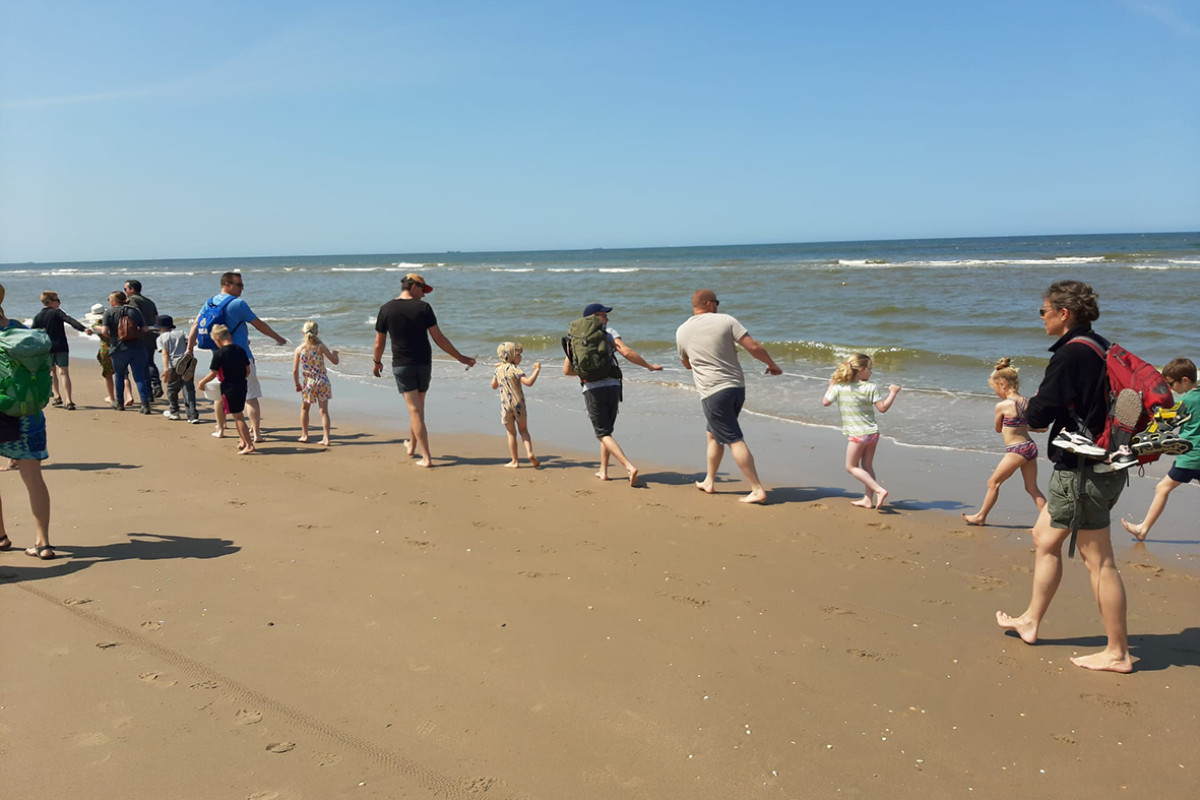 Groep mensen loopt langs de branding en houden en kornet vast