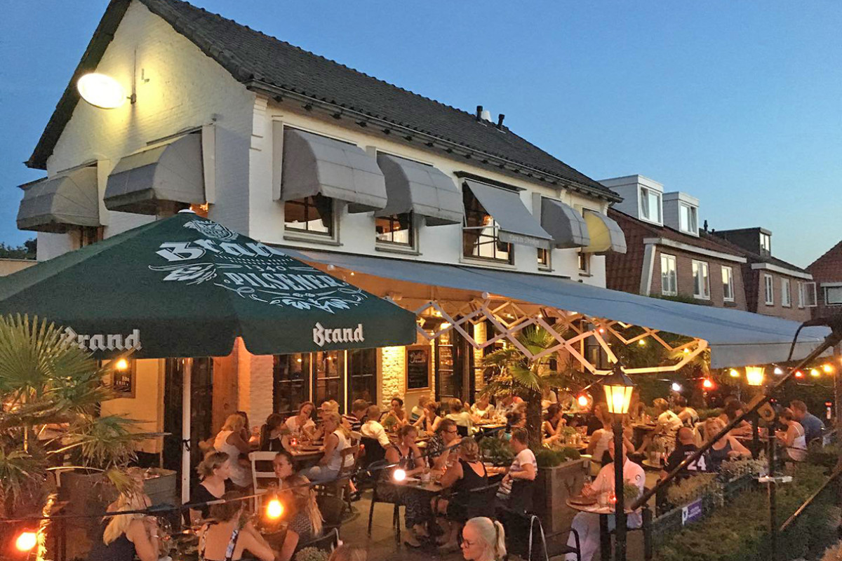 Restaurant halfweg met mensen die 's avonds buiten op het terras zitten.