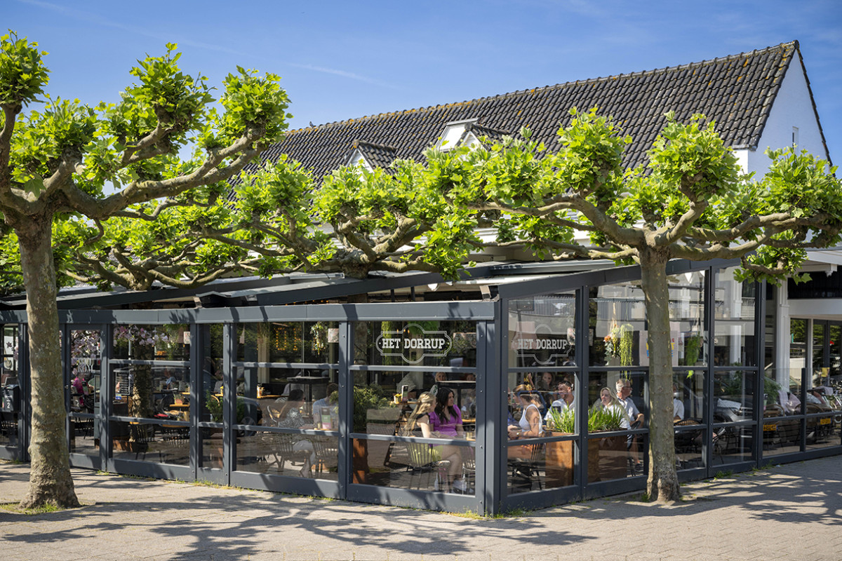 Buitenkant van Restaurant Het Dorrup met blauwe lucht en groene bomen ervoor.