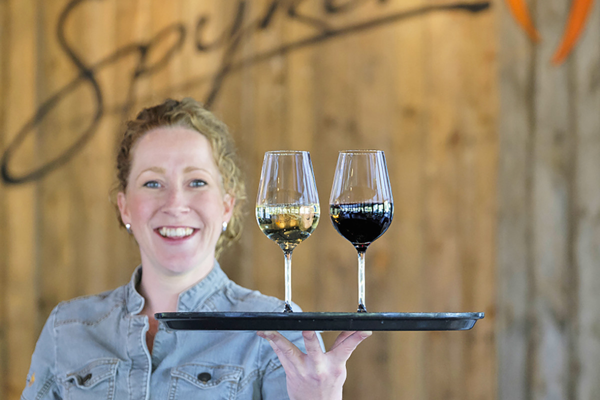 Serveerster van Restaurant Spijkers Heemskerk met een dienblad met twee wijnglazen.