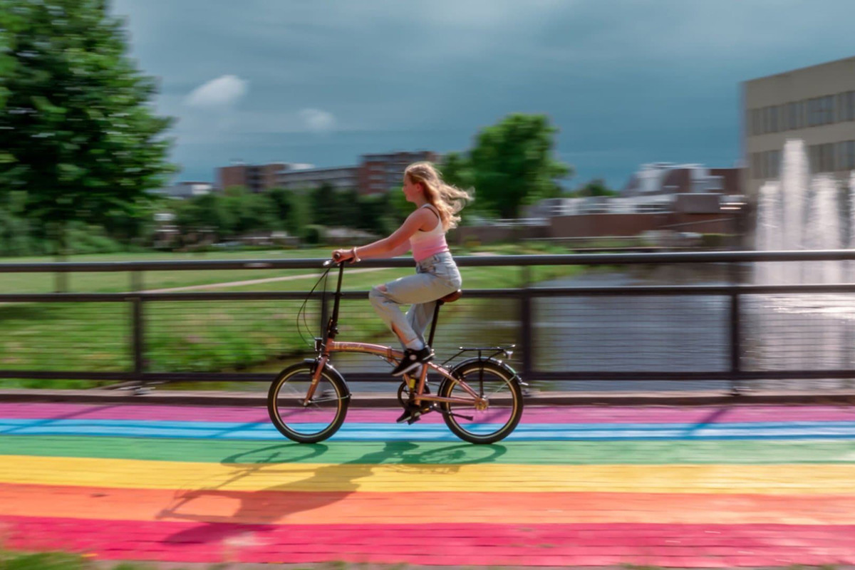 Een meisje fietst op een regenboogkleurig pad.