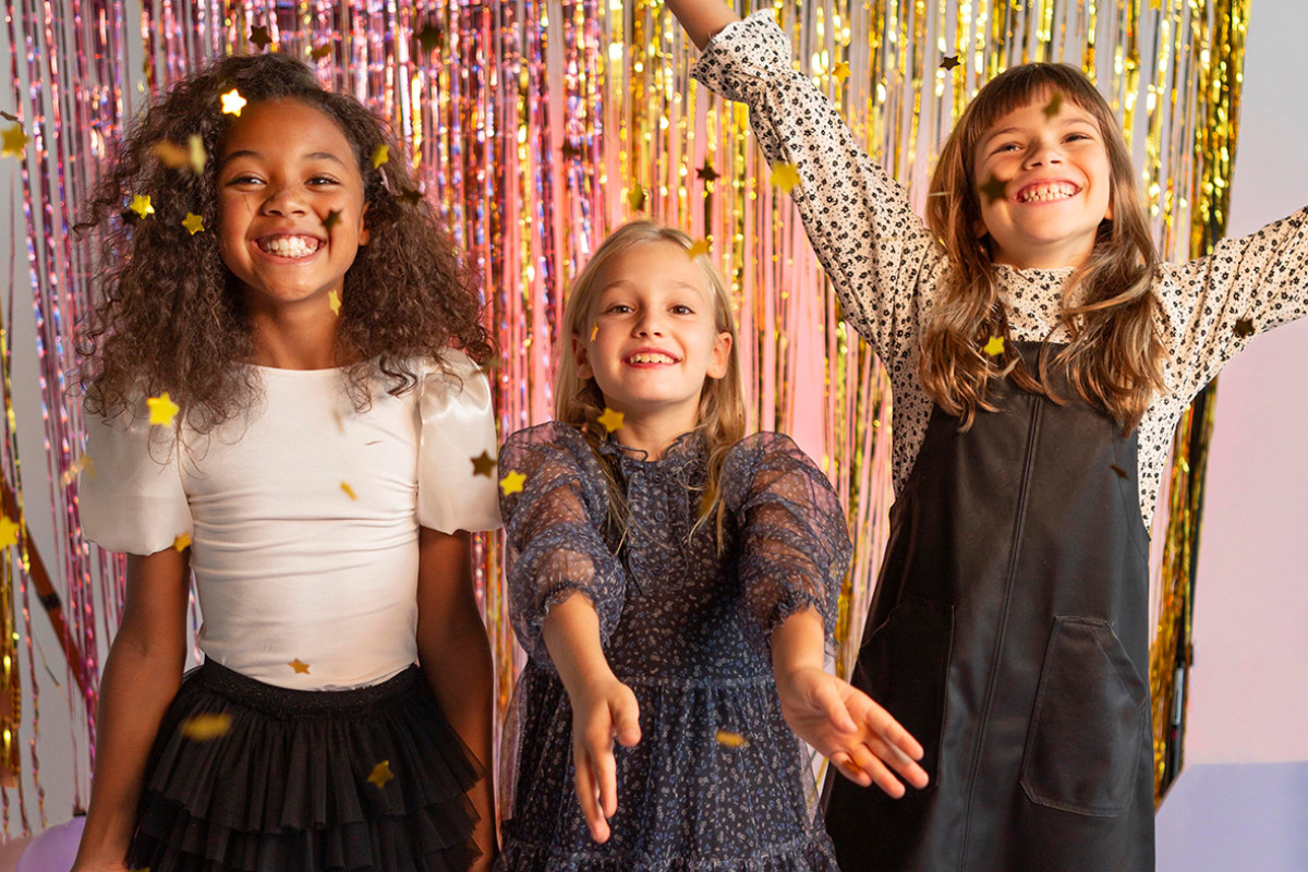 3 meisjes staan voor een glittergordijn op een feestje.