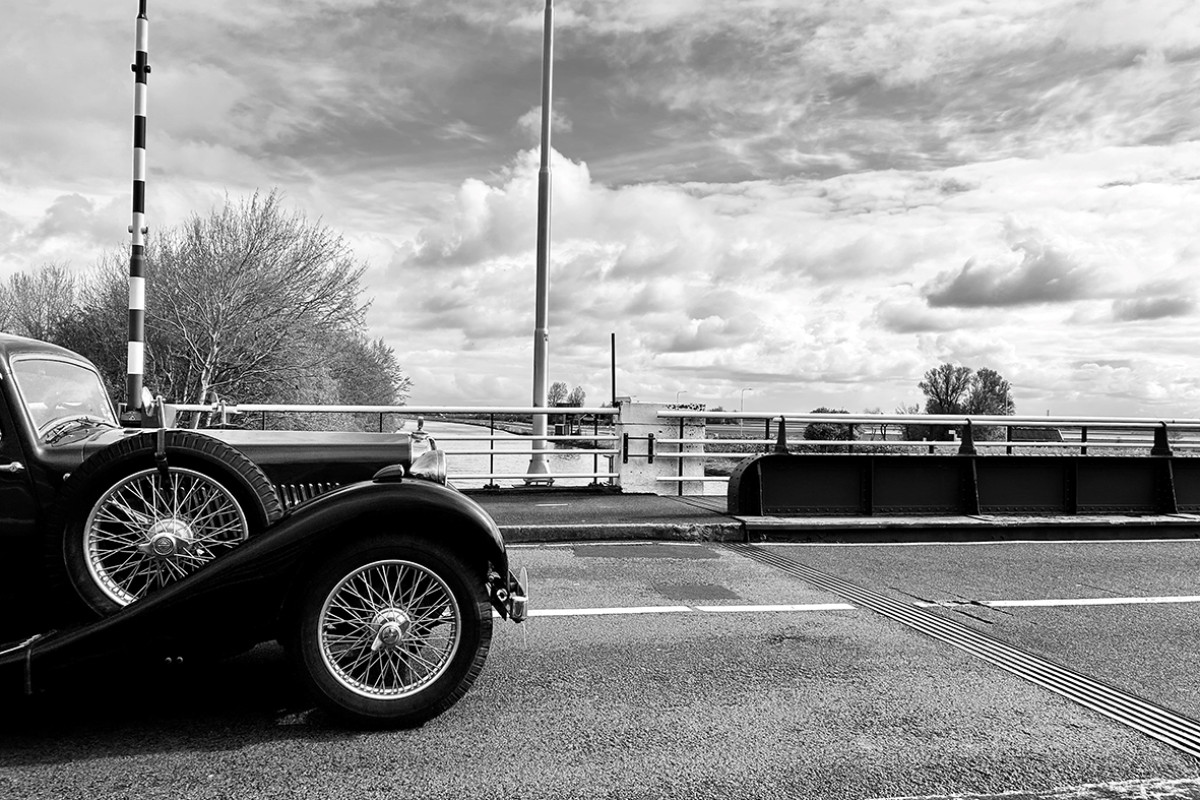 Zwart wit foto van brug met oldtimer erop