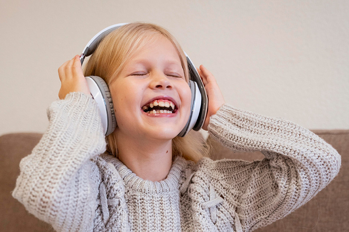 Lachen meisje met grijze trui heeft koptelefoon op