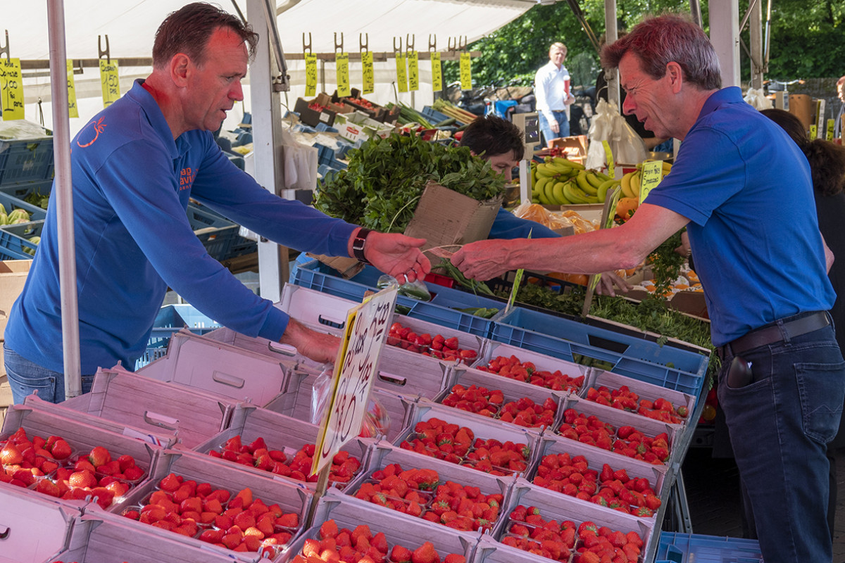 Marktkoopman in kraam verkoopt aardbeien.