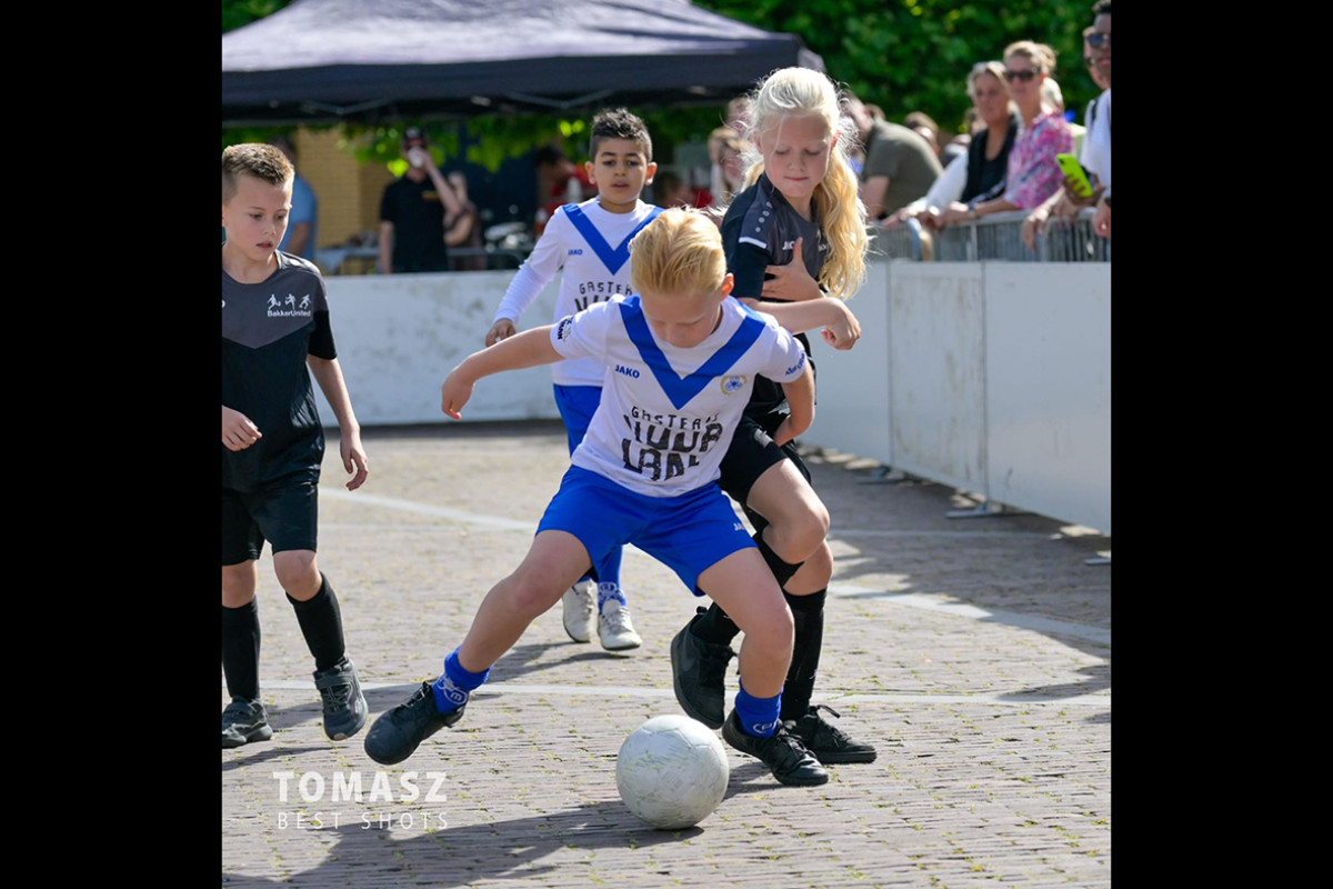 Jongen en meisje voetballen op een plein