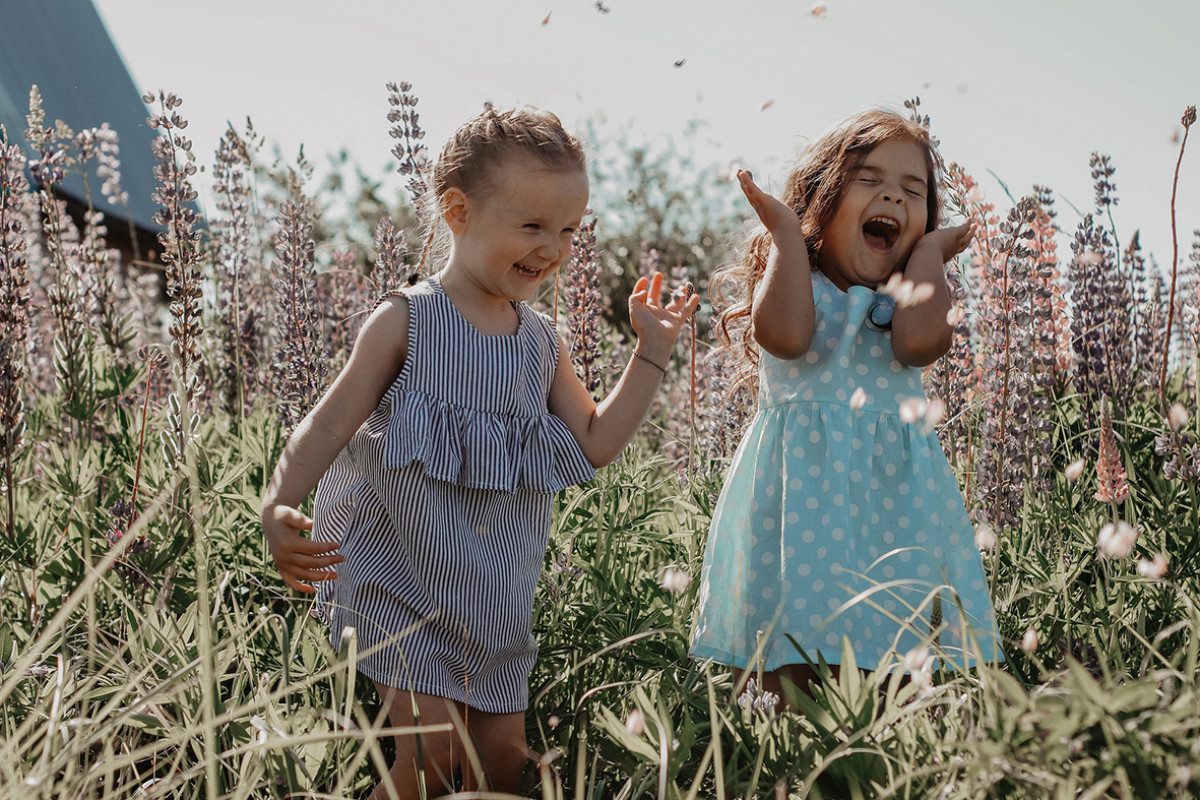 twee meisjes staan tussen bloemen