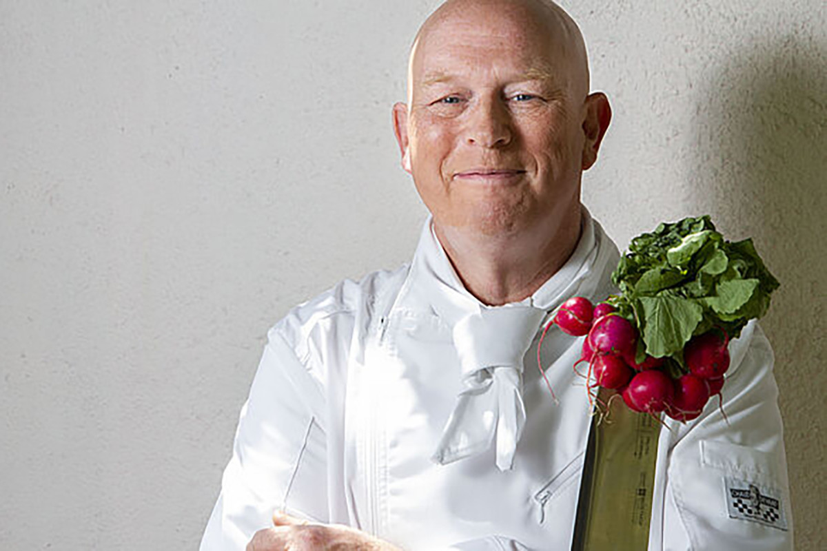 Portretfoto van chefkok Pierre Wind met een bosje radijs op z'n schouder